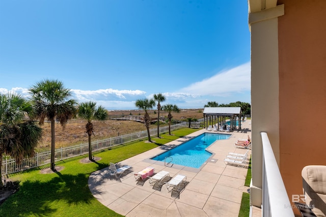 view of swimming pool featuring a patio area, a rural view, and a lawn