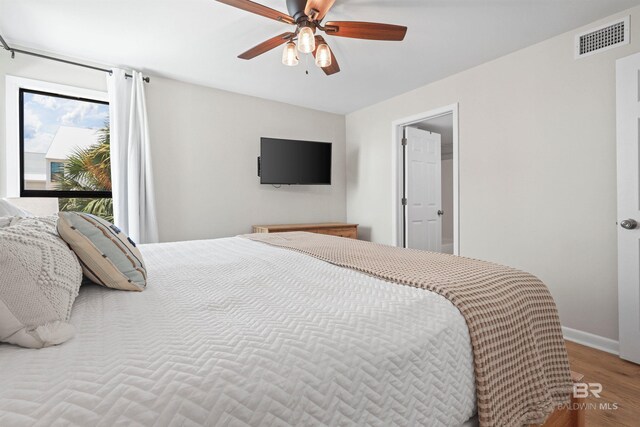 bedroom featuring visible vents, baseboards, a ceiling fan, and wood finished floors