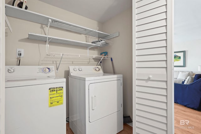 washroom with laundry area, wood finished floors, and washing machine and dryer