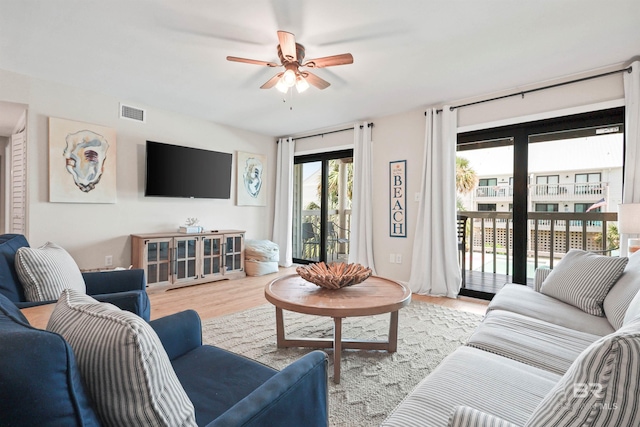 living room featuring wood finished floors, a ceiling fan, and visible vents