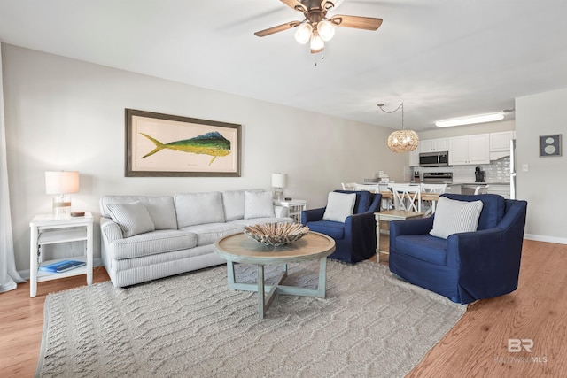 living area featuring light wood-style floors and ceiling fan with notable chandelier
