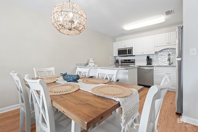 dining area with light wood-style floors, visible vents, and baseboards