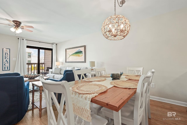 dining area featuring ceiling fan with notable chandelier, baseboards, and wood finished floors