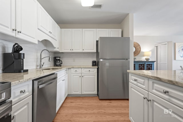 kitchen with light wood-style floors, appliances with stainless steel finishes, a sink, and white cabinets