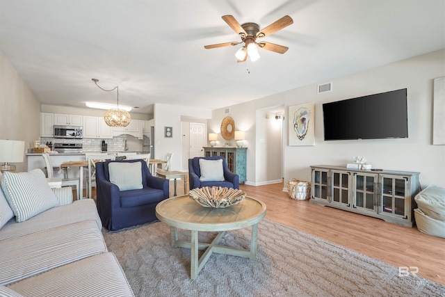 living area with light wood finished floors, visible vents, baseboards, and ceiling fan