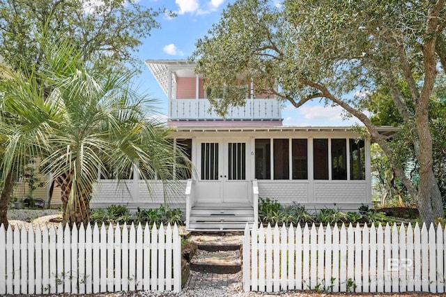 view of front of property featuring a sunroom, a balcony, and a fenced front yard