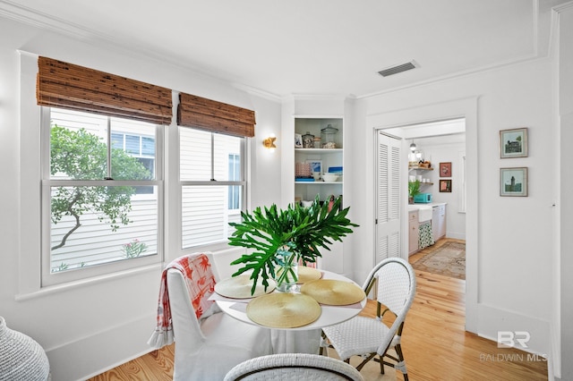 dining room featuring light wood finished floors, visible vents, and ornamental molding