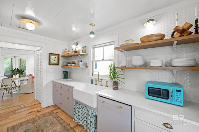 kitchen featuring open shelves, a sink, light countertops, light wood-style floors, and decorative backsplash