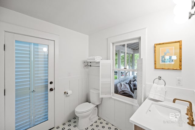 half bathroom with wainscoting, a sink, and toilet