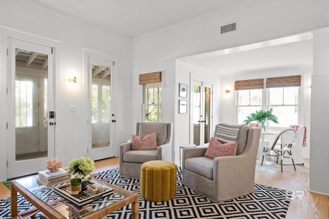 living area with a wealth of natural light, light wood-style floors, visible vents, and french doors