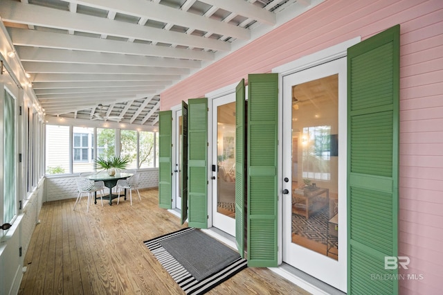 exterior space featuring wooden walls, vaulted ceiling with beams, and wood finished floors