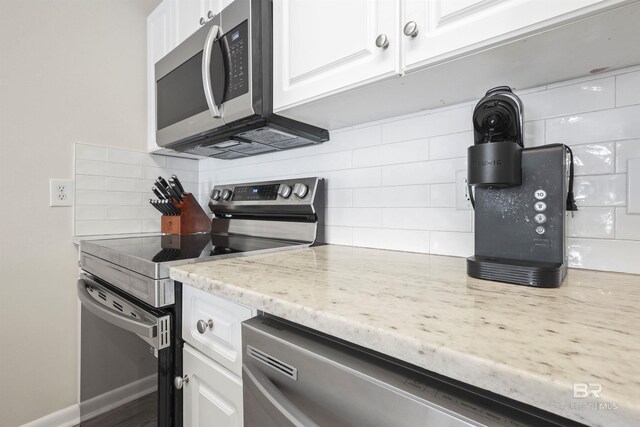 26115 Perdido Beach Blvd Unit 5D, Orange Beach, AL 36561 - kitchen with appliances with stainless steel finishes, tasteful backsplash, white cabinets, light stone counters, and baseboards