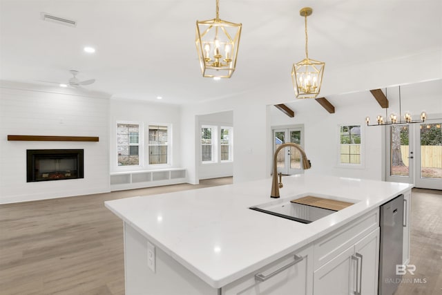 kitchen with stainless steel dishwasher, pendant lighting, open floor plan, and a sink