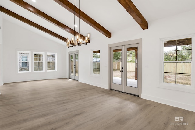 unfurnished living room with vaulted ceiling with beams, an inviting chandelier, light wood-type flooring, and french doors