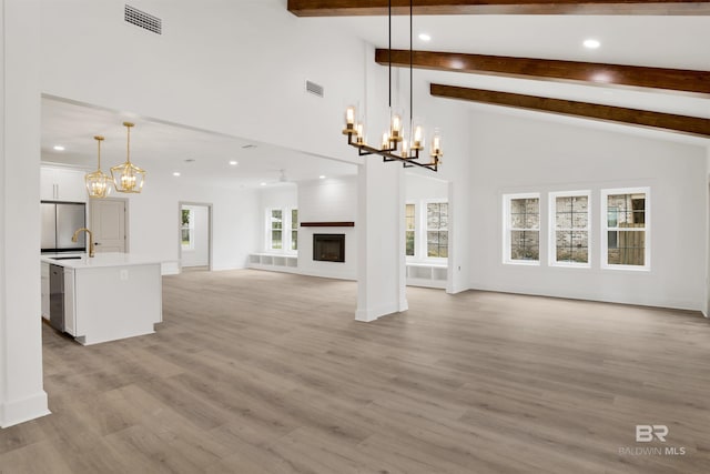 unfurnished living room with beam ceiling, visible vents, a fireplace, and light wood-style flooring