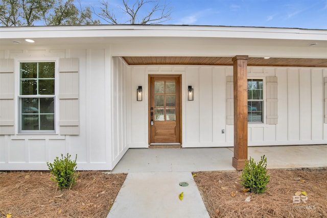 property entrance featuring covered porch and board and batten siding