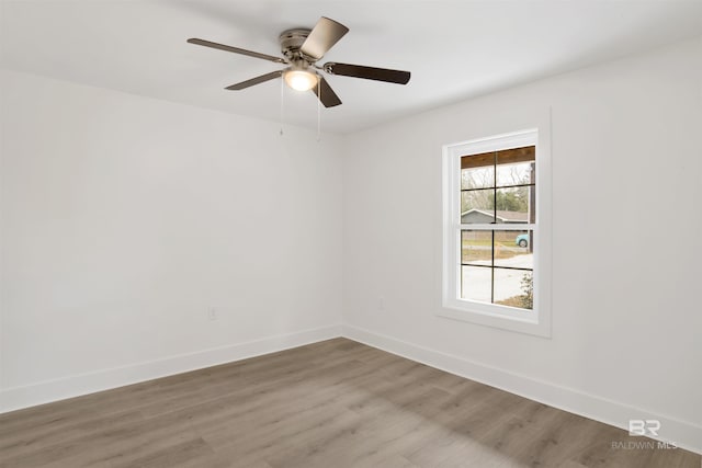 empty room with light wood finished floors, baseboards, and a ceiling fan