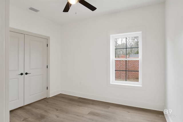 unfurnished bedroom with a closet, visible vents, a ceiling fan, light wood-type flooring, and baseboards