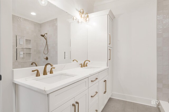 full bathroom featuring a sink, a tile shower, baseboards, and double vanity