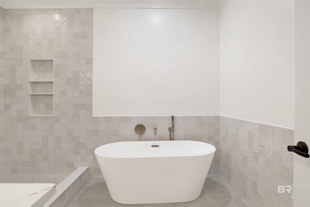 full bath featuring a freestanding tub, wainscoting, tile walls, and tile patterned floors