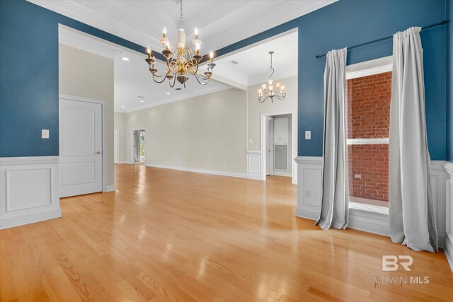 unfurnished room featuring light wood-type flooring, a chandelier, and crown molding