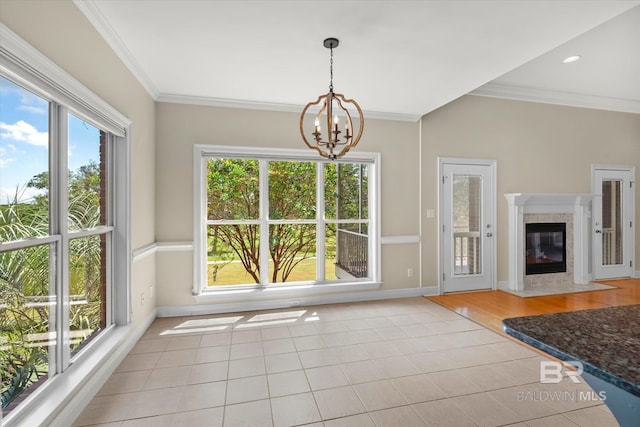 unfurnished dining area featuring ornamental molding, a high end fireplace, light wood-type flooring, and a chandelier