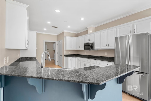 kitchen featuring white cabinets, stainless steel fridge, kitchen peninsula, a breakfast bar area, and black stovetop