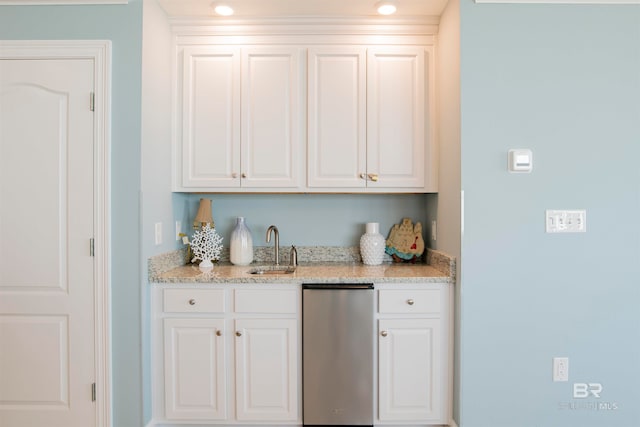 bar featuring dishwasher, sink, light stone counters, and white cabinetry