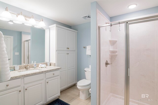 bathroom with tile patterned flooring, vanity, walk in shower, and toilet