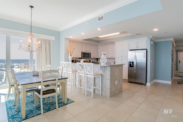 kitchen with hanging light fixtures, stainless steel appliances, crown molding, and white cabinetry