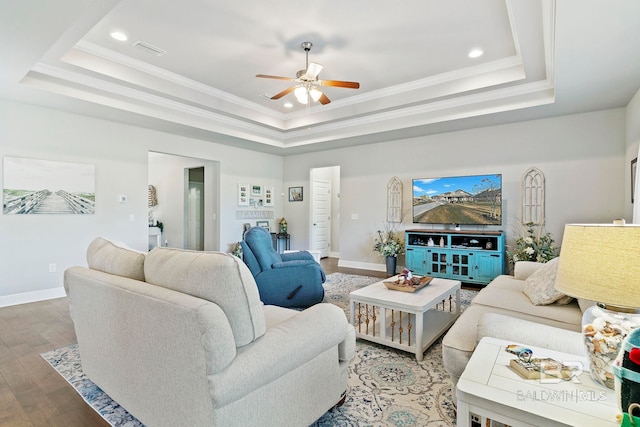 living room featuring hardwood / wood-style flooring, crown molding, and a raised ceiling