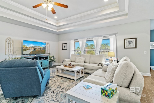 living room with crown molding, ceiling fan, a tray ceiling, and light hardwood / wood-style floors