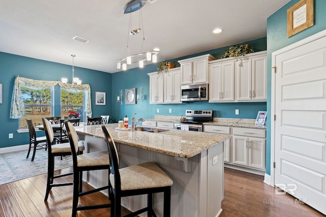 kitchen with pendant lighting, stainless steel appliances, sink, and white cabinets