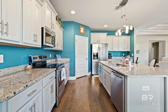 kitchen with sink, white cabinetry, hanging light fixtures, stainless steel appliances, and a kitchen island with sink