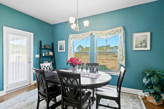 dining space with hardwood / wood-style floors and a notable chandelier