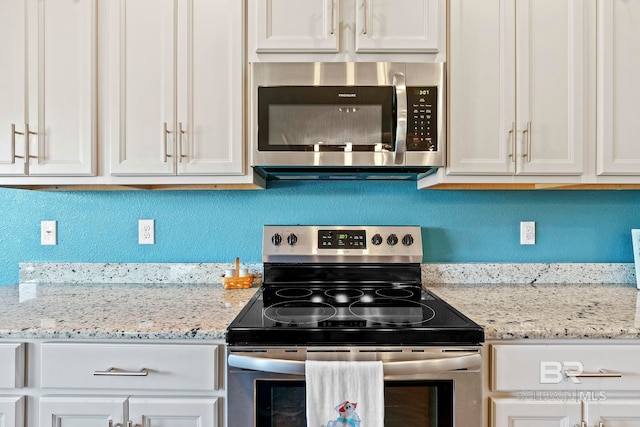 kitchen with light stone countertops, stainless steel appliances, and white cabinets