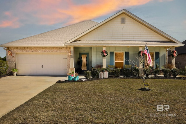 view of front of house featuring a yard, a garage, and covered porch