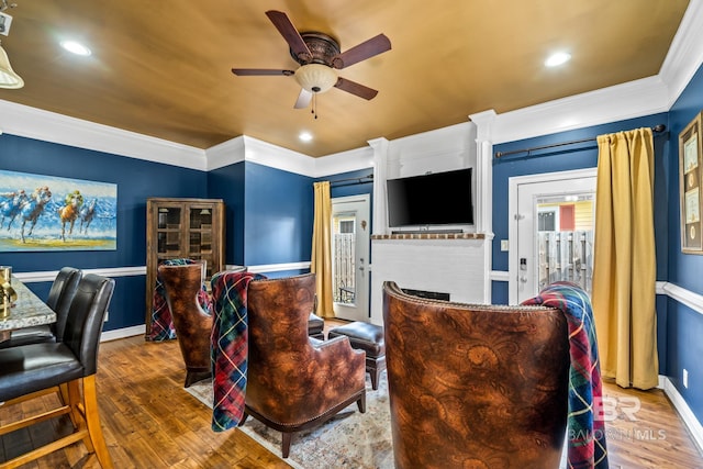 living room with ceiling fan, crown molding, dark hardwood / wood-style floors, and a brick fireplace