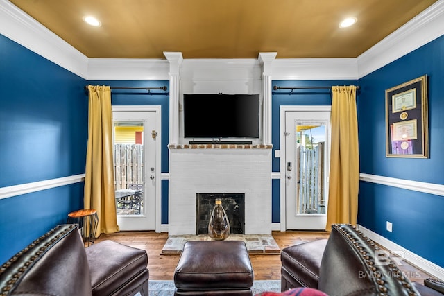 living room with light hardwood / wood-style flooring, ornamental molding, and a brick fireplace