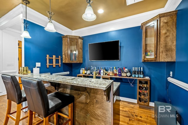 bar featuring decorative light fixtures, crown molding, dark wood-type flooring, and light stone countertops