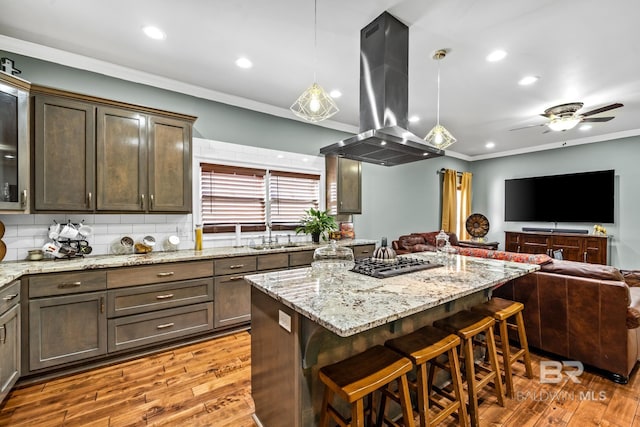 kitchen featuring light hardwood / wood-style floors, light stone countertops, ceiling fan, hanging light fixtures, and island exhaust hood