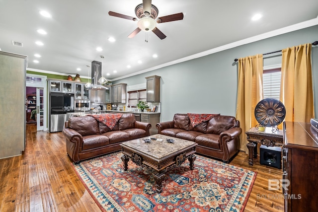 living room featuring crown molding, hardwood / wood-style floors, ceiling fan, and a wealth of natural light