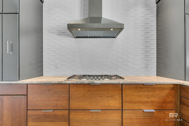 kitchen with backsplash, stainless steel gas stovetop, and wall chimney exhaust hood