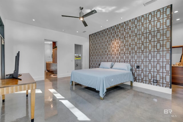 bedroom with ceiling fan, ensuite bath, and concrete floors