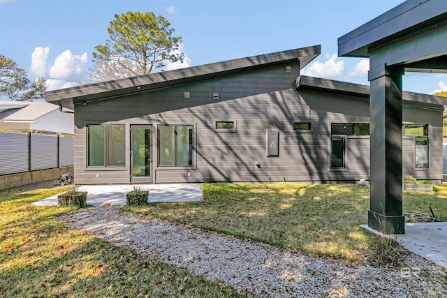 back of property featuring a patio area and a lawn