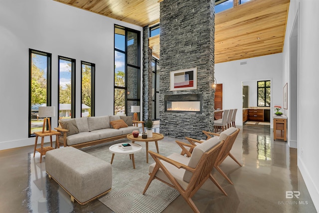 living room featuring wood ceiling, a stone fireplace, and a towering ceiling