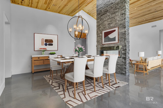 dining area with a chandelier, a stone fireplace, concrete floors, high vaulted ceiling, and wood ceiling