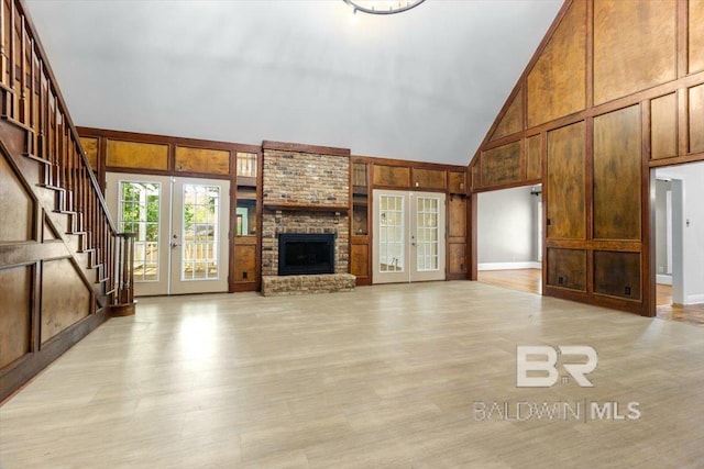 6505 Charing Wood Dr, Mobile, AL 36695 - unfurnished living room featuring french doors, high vaulted ceiling, stairs, a fireplace, and light wood-style floors