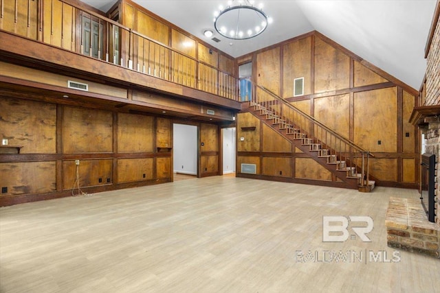 6505 Charing Wood Dr, Mobile, AL 36695 - unfurnished living room with high vaulted ceiling, stairs, wood walls, a chandelier, and a decorative wall