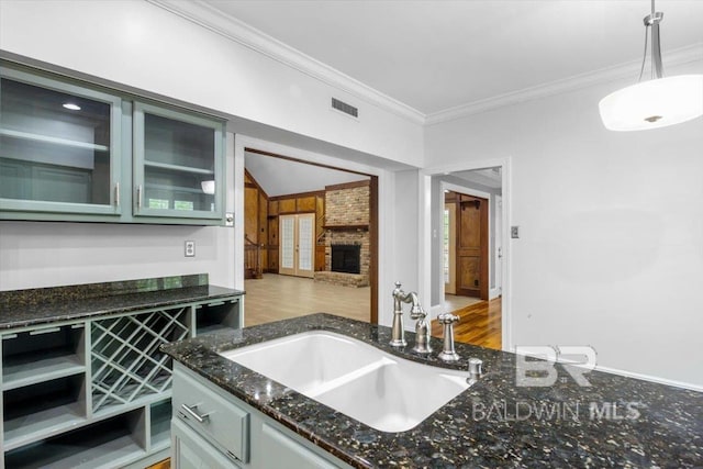 6505 Charing Wood Dr, Mobile, AL 36695 - kitchen with crown molding, dark stone counters, a fireplace, glass insert cabinets, and decorative light fixtures